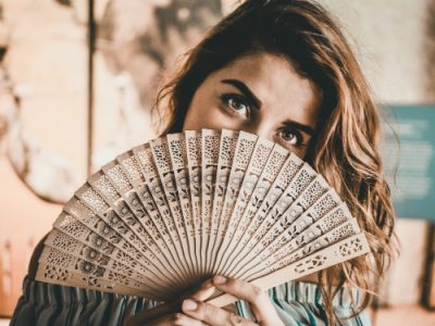 what causes hot flushes | woman with a fan | Perpetual Wellbeing