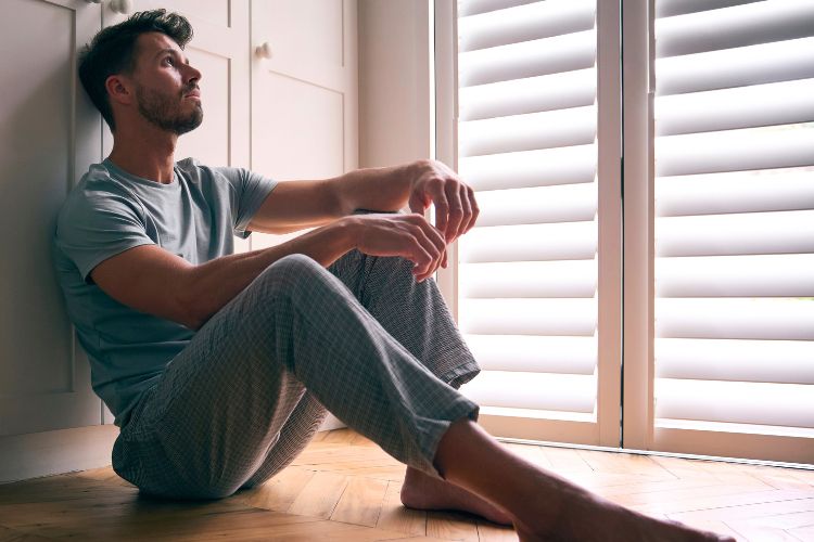 man sitting on floor in darkened room used on a blog about metabolic dysfunction