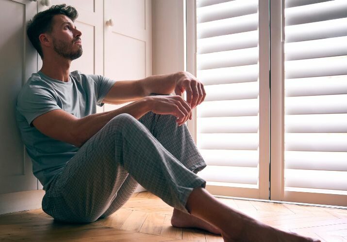 man sitting on floor in darkened room used on a blog about metabolic dysfunction